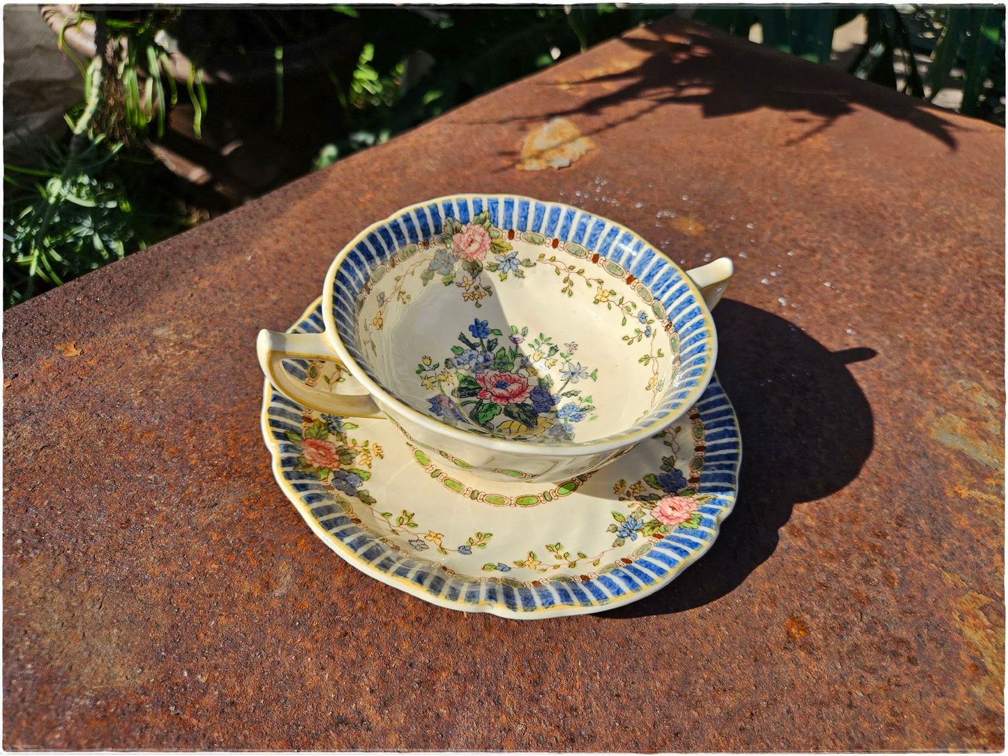 Floral teacup and saucer set on a textured surface with natural background