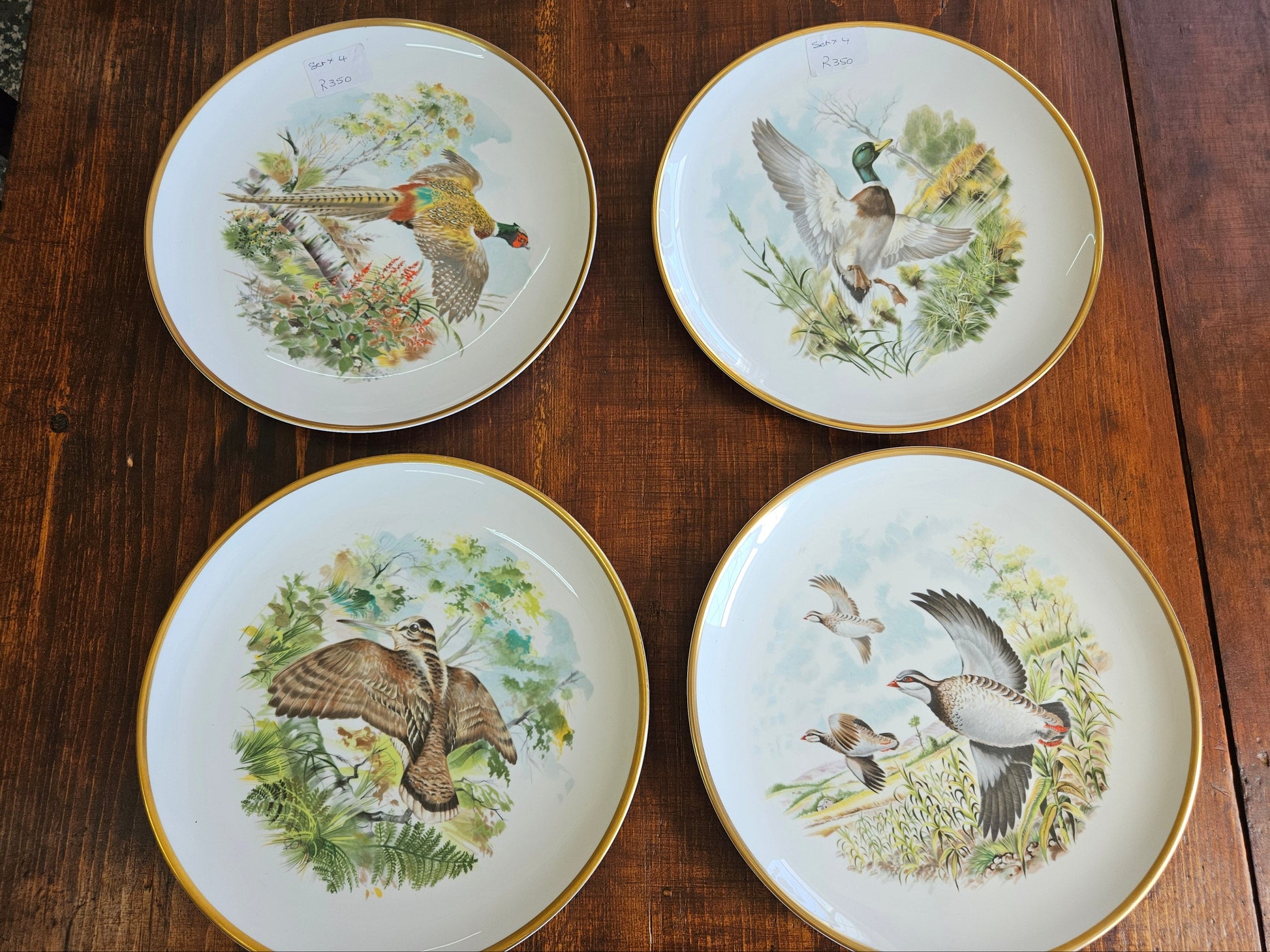 Four decorative plates with bird illustrations