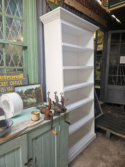 Large white bookshelf or shop fitting pictured next to a rustic mint green cupboard with vintage grinders. 